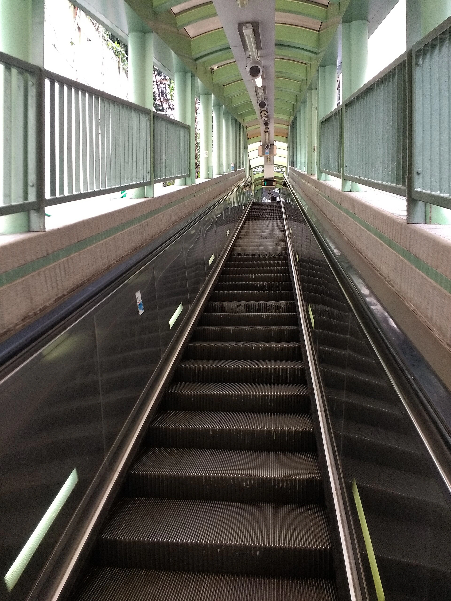 Covered Central Mid-Levels escalator passing between dense urban buildings