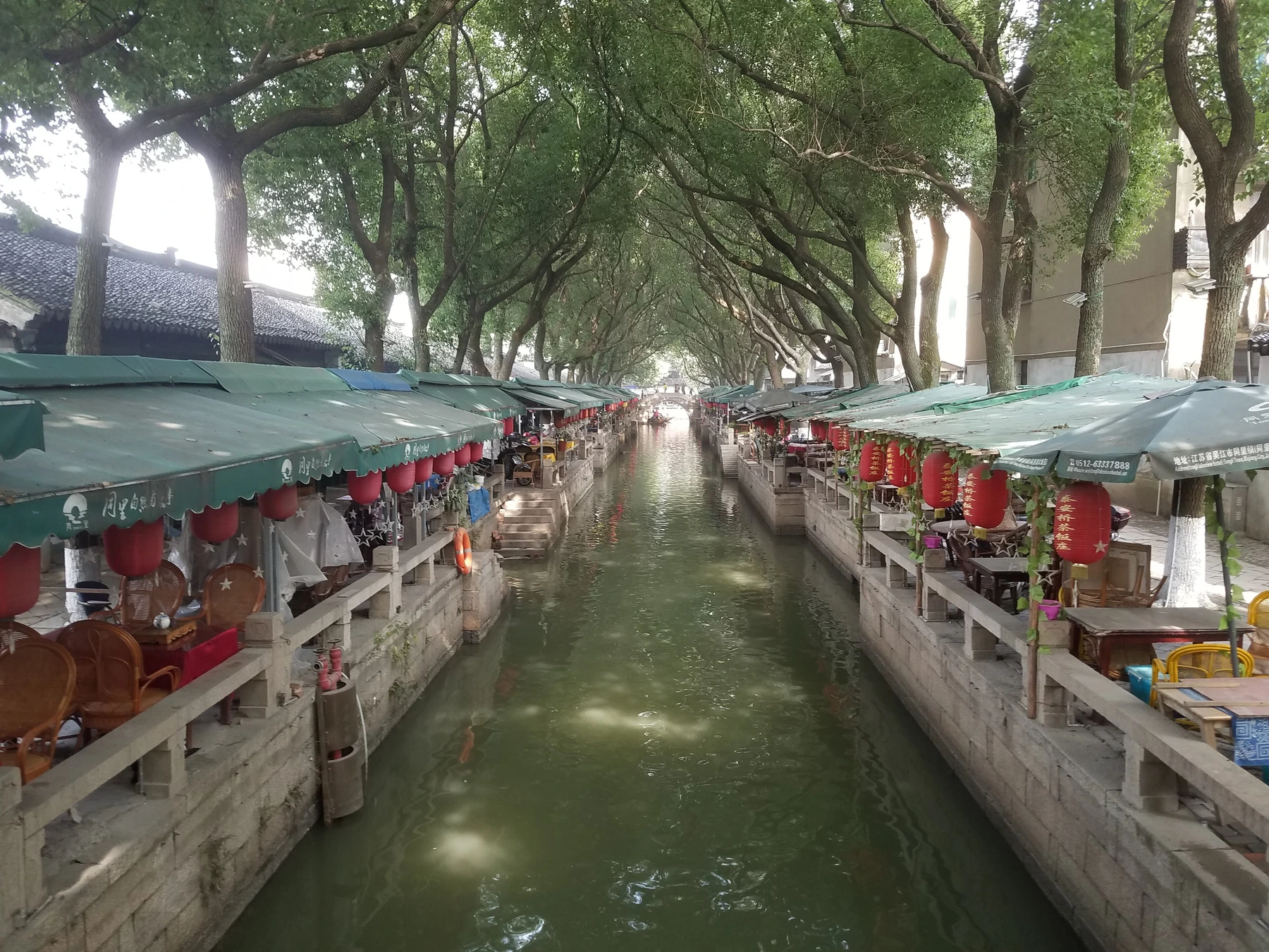 Long canal lined by trees, terraces and lanterns in Tongli