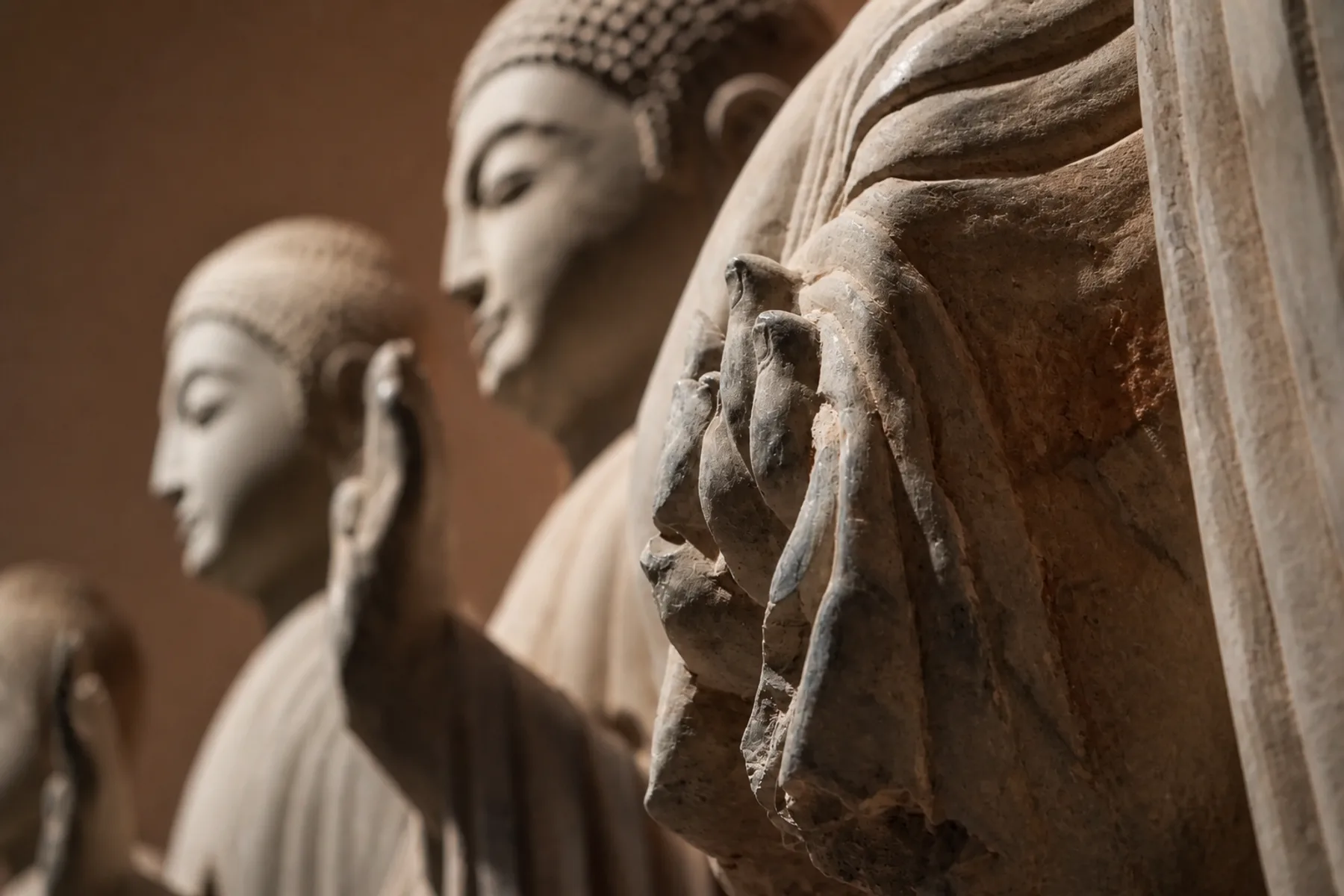 Close-up of a weathered Buddhist stone sculpture hand and robe folds