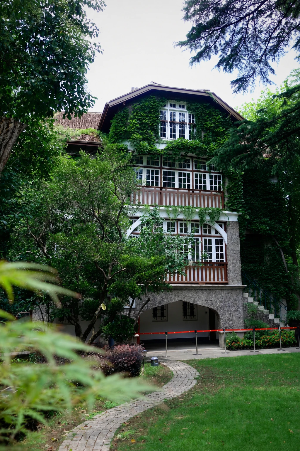A historic garden house framed by ivy and mature trees at Sinan Mansions