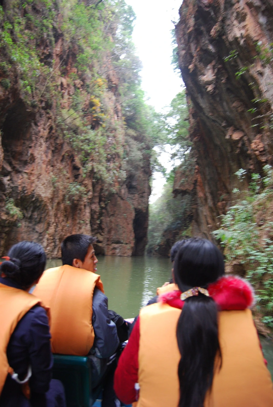 Visitors traveling by small boat through Jiuxiang's narrow river gorge