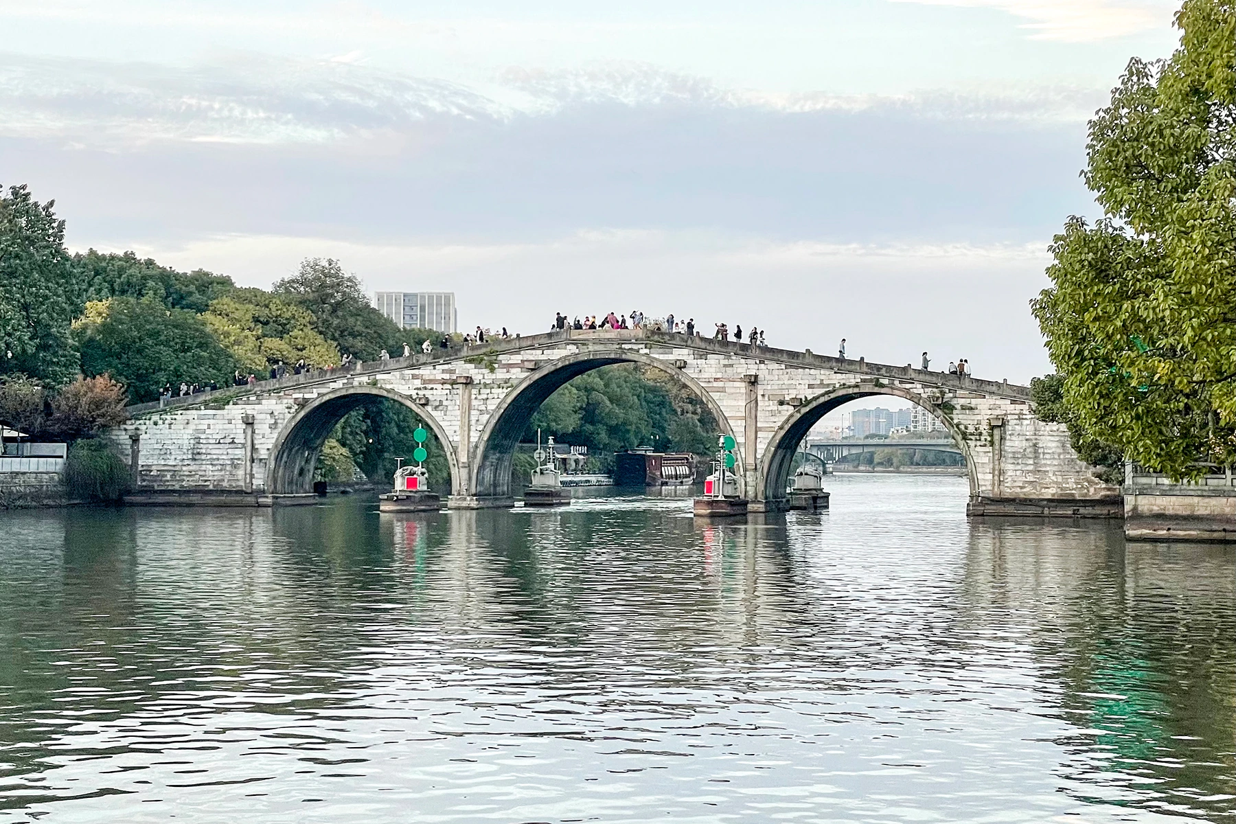 Gongchen Bridge seen across the canal with its stone arches reflected in the water